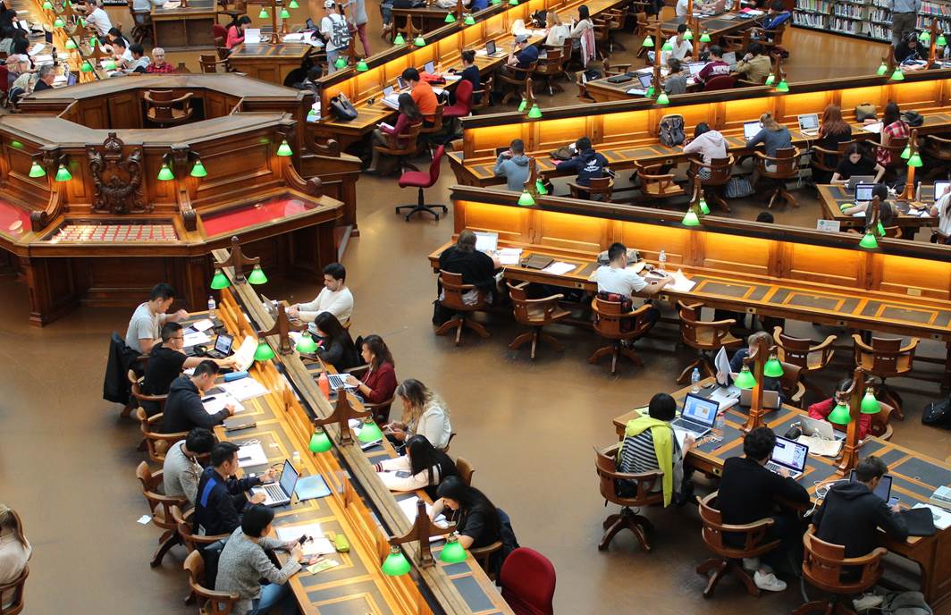 Birds eye view of a university library with students studying at rows of desks